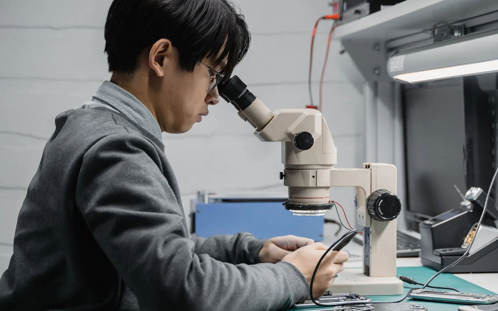 Technician inspecting an iPhone display assembly under a microscope at a repair bench