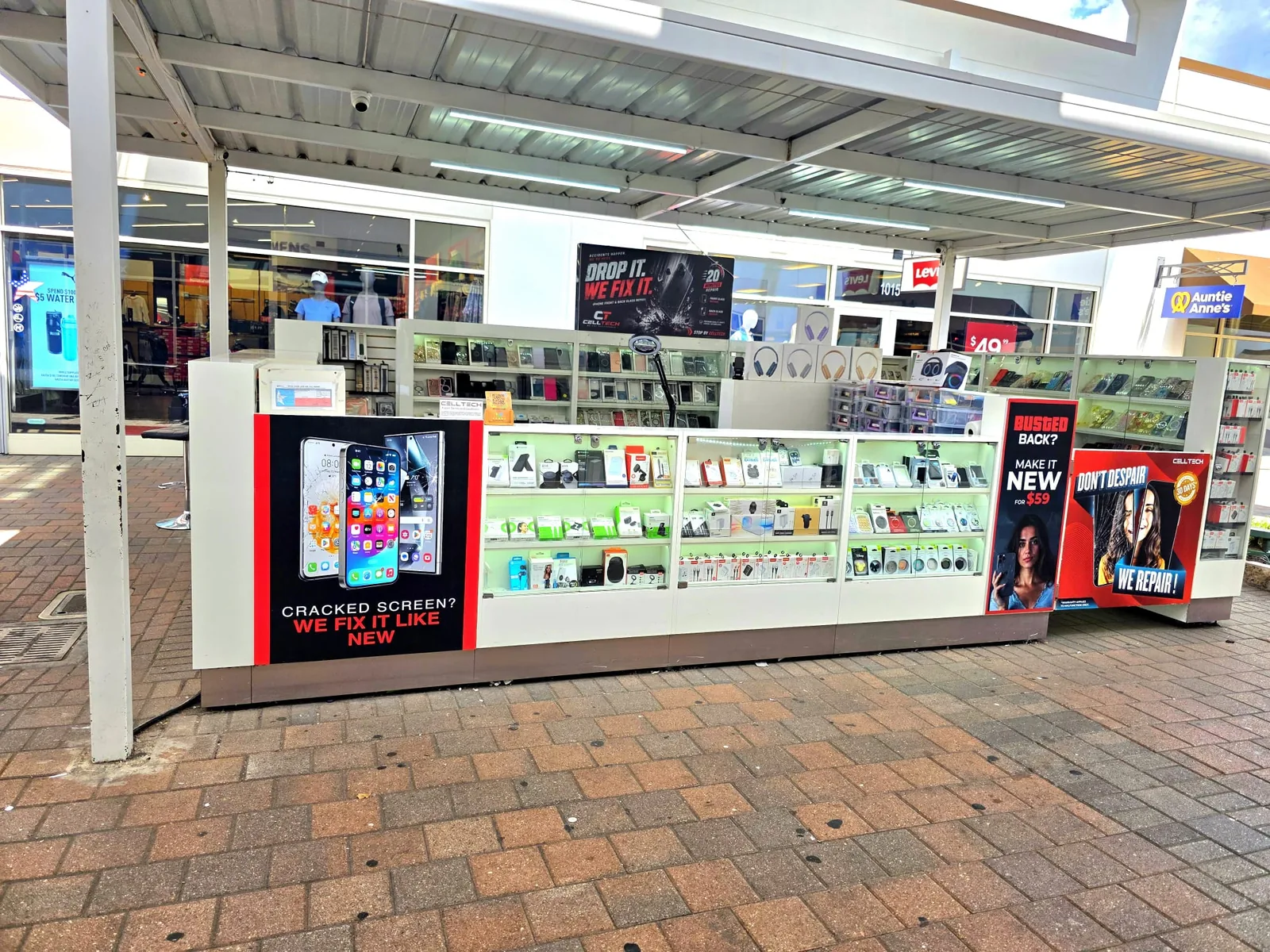 The CELLTECH counter at Grand Prairie Premium Outlets, headed by a “Cracked screen? We fix it like new” iPhone repair panel