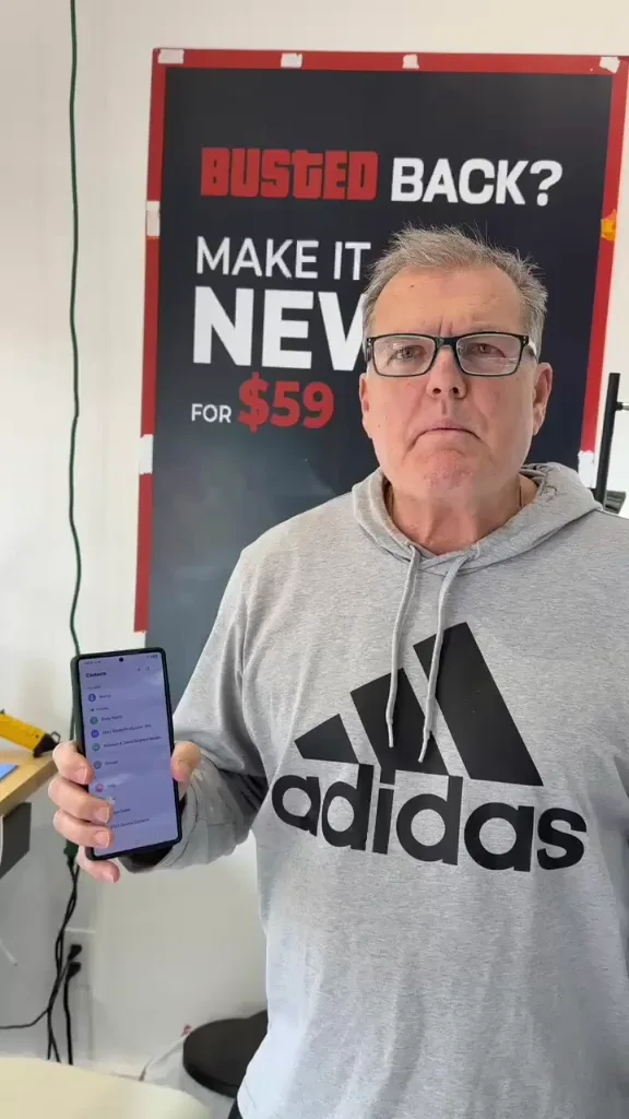 A CELLTECH customer holding up his repaired phone in the Grand Prairie store
