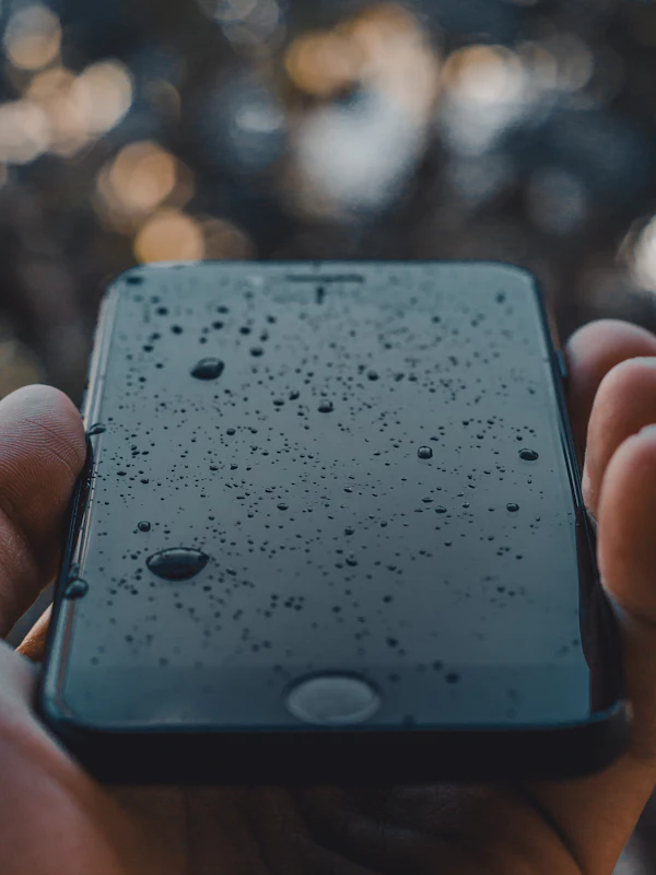 Water droplets across the screen of a phone held in both hands