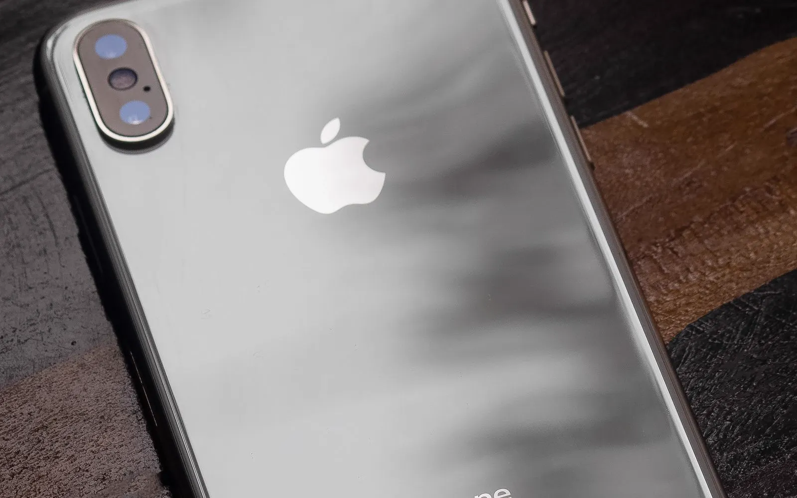 The rear panel of a smartphone lying face down on a dark table