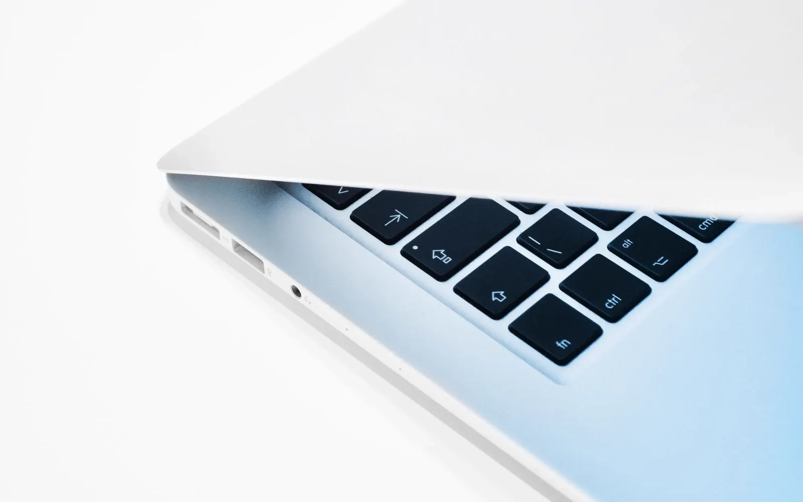 A part-closed MacBook seen from the side, showing its keyboard edge and ports