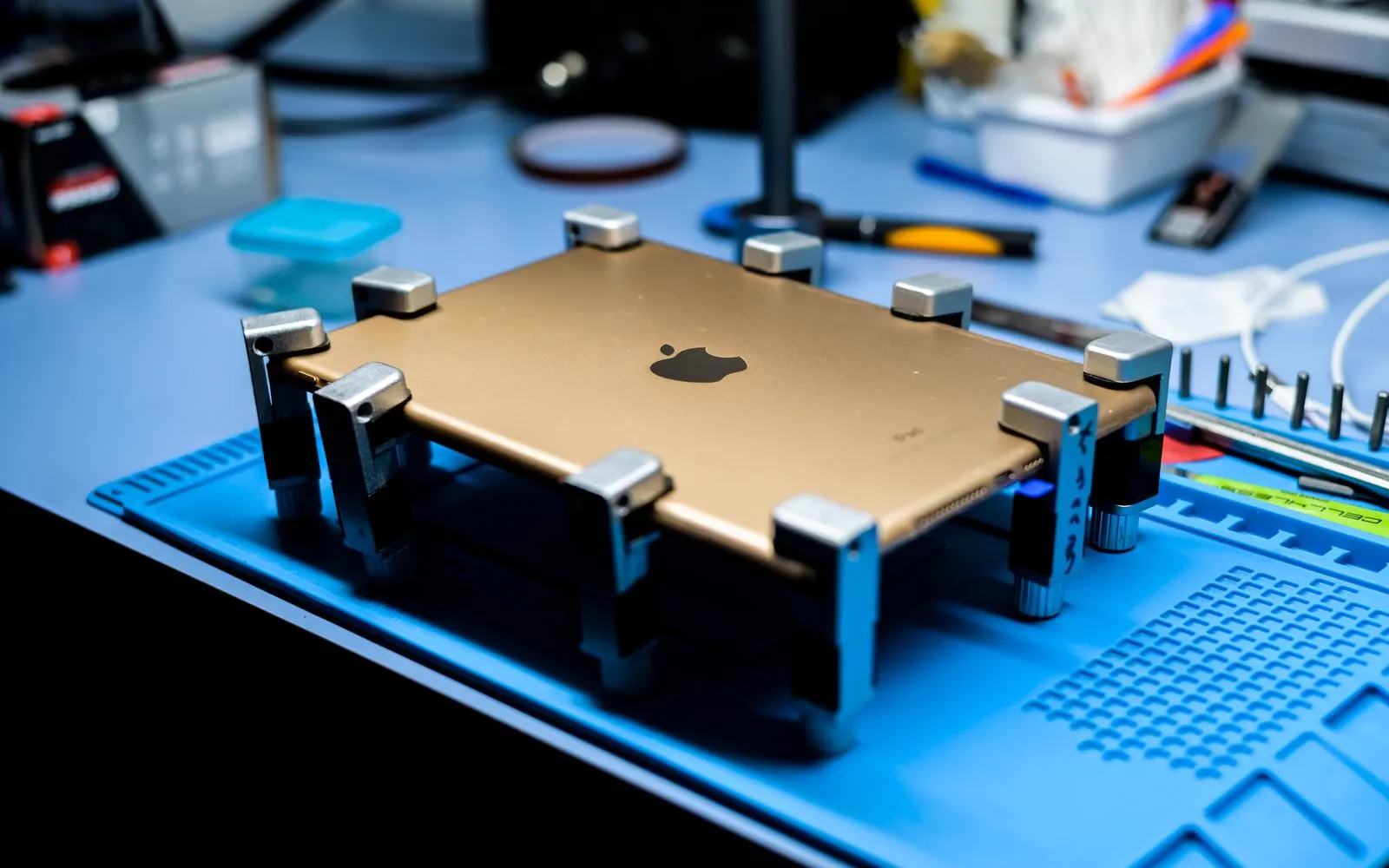 A tablet being worked on at a repair bench with tools around it