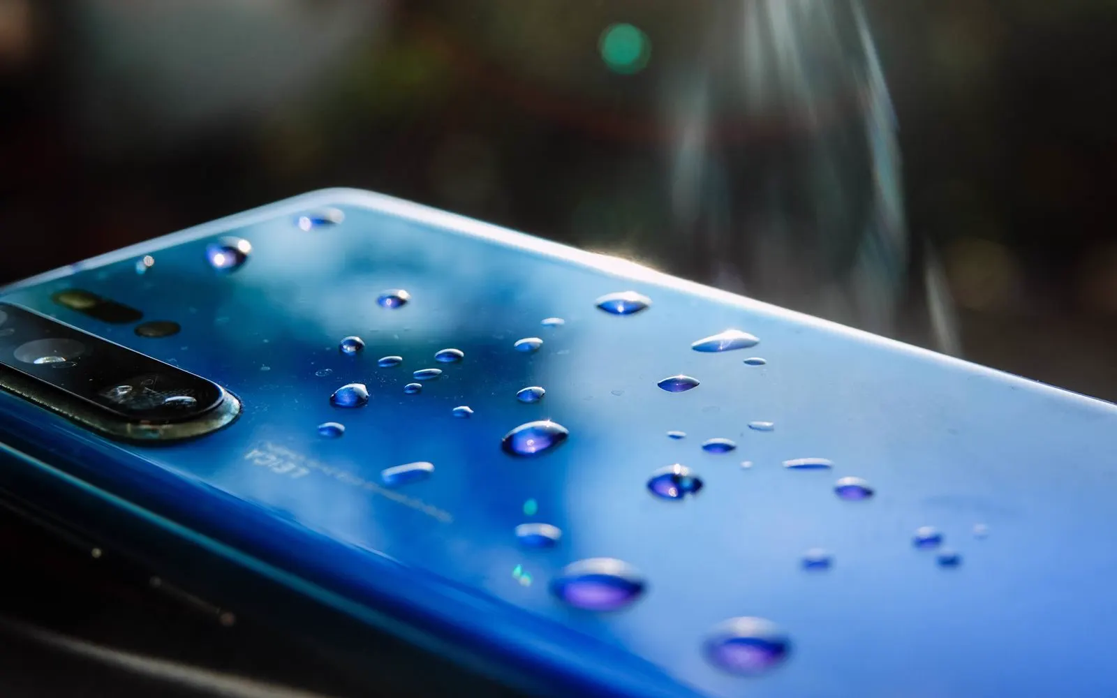 Water droplets beaded on the back of a blue smartphone