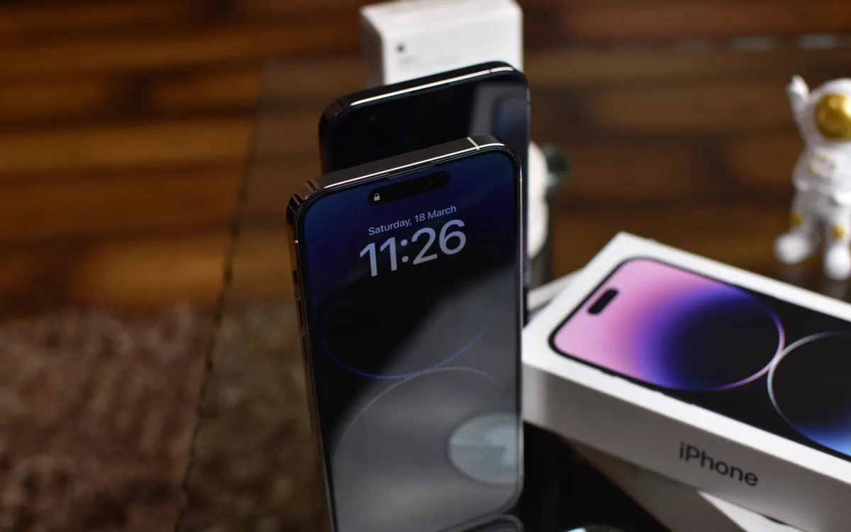 An iPhone 14 Pro on a desk, its Dynamic Island and display lit