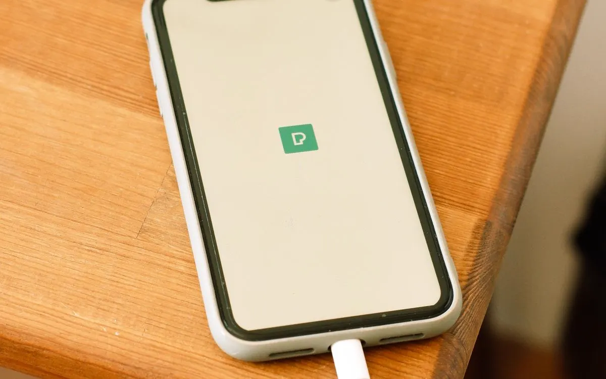 A smartphone plugged into a charger on a wooden table