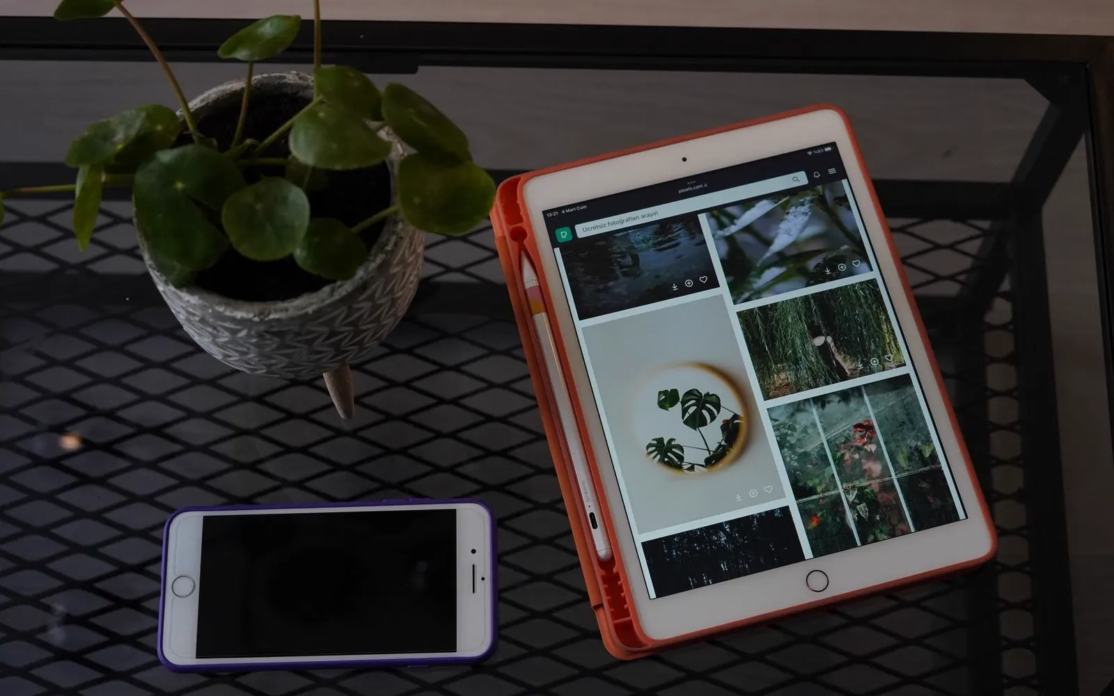 A tablet showing a photo library on a desk beside a smartphone