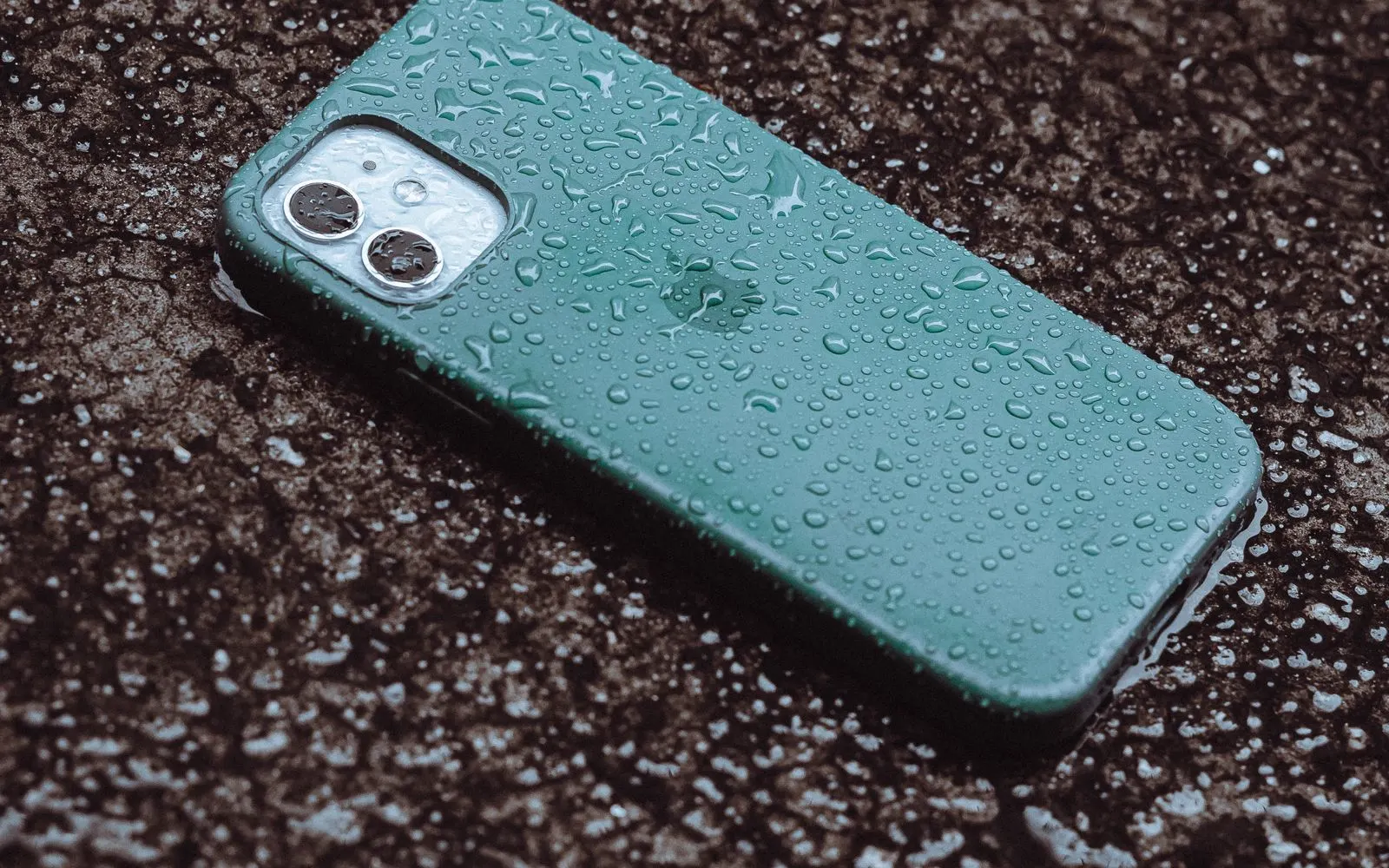 A rain-soaked smartphone lying on wet pavement