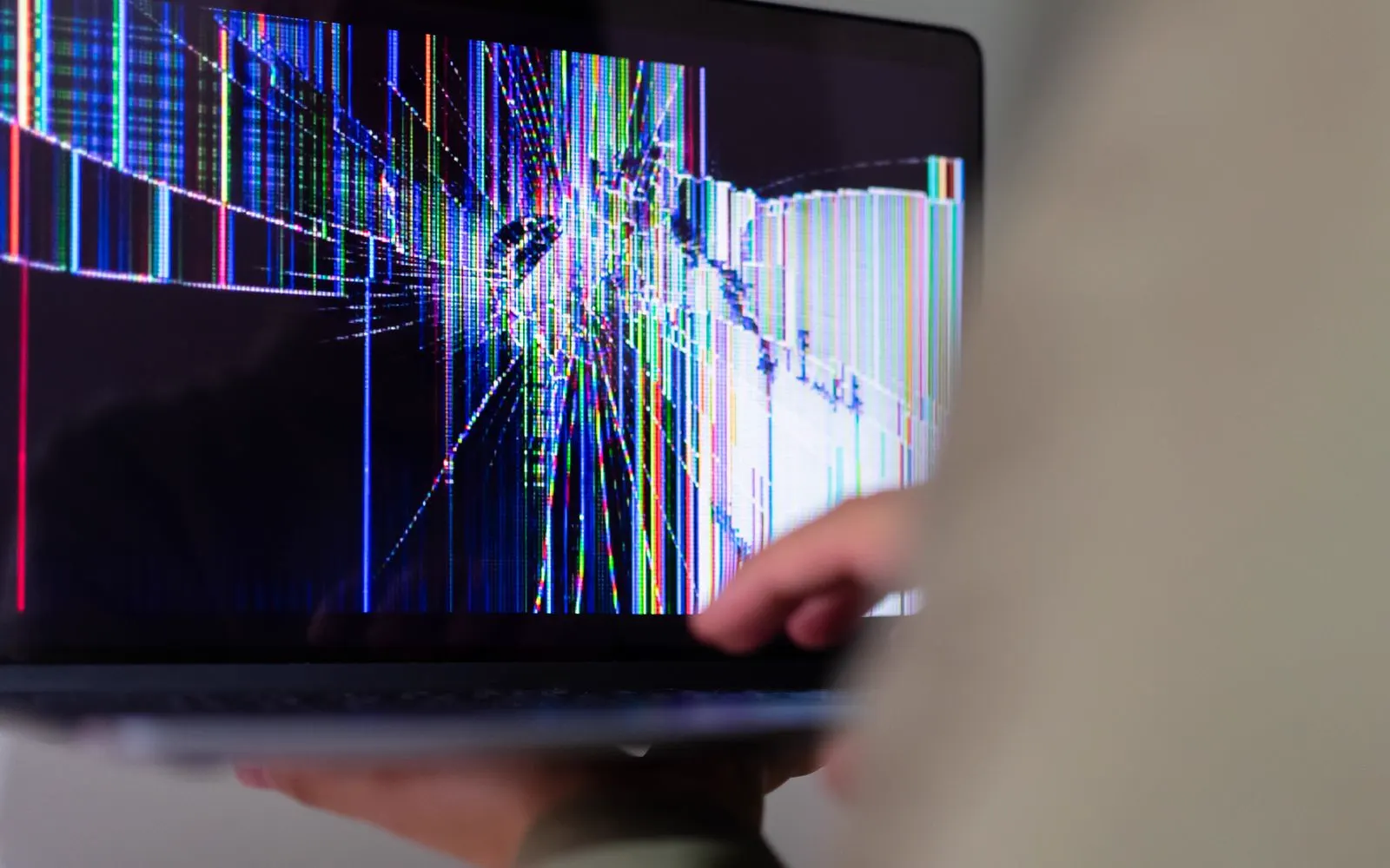 A close-up of a cracked laptop screen showing colour distortion