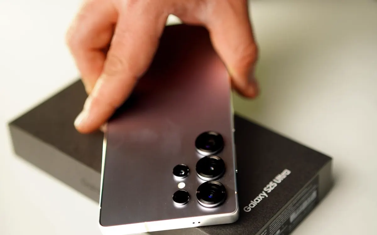 A hand holding a Samsung Galaxy S25 Ultra above its box