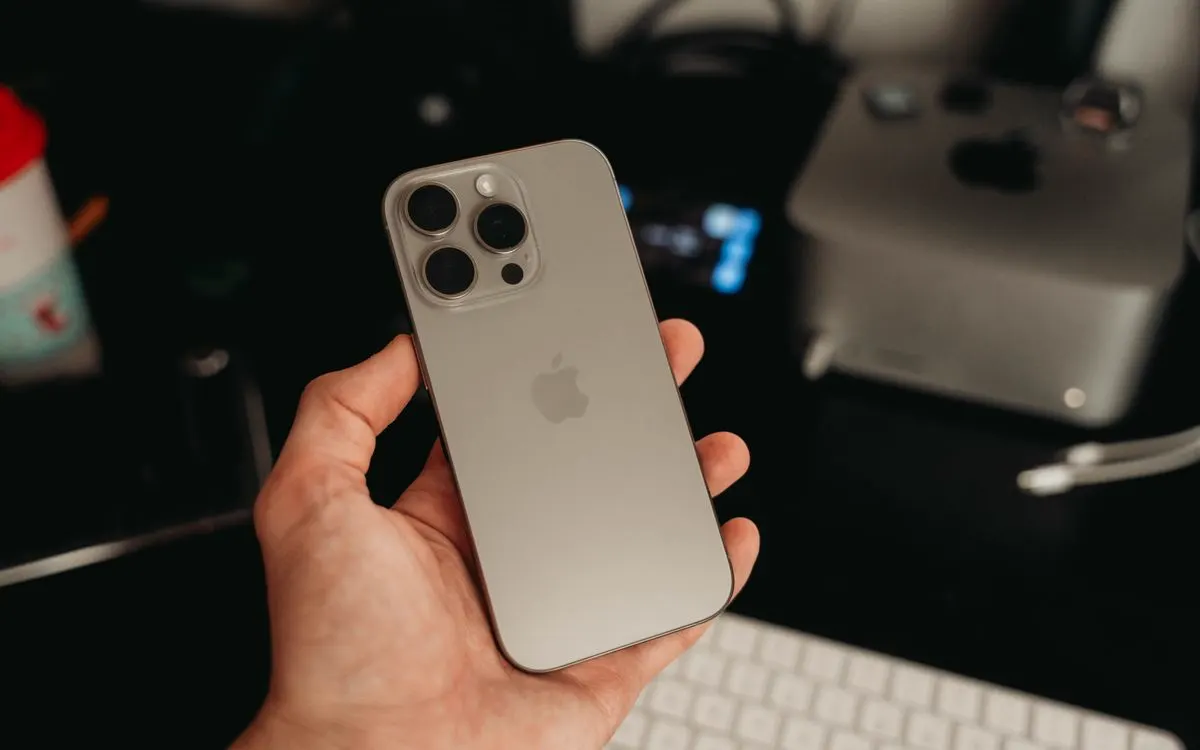 A hand holding a modern iPhone at eye level, its screen facing the camera