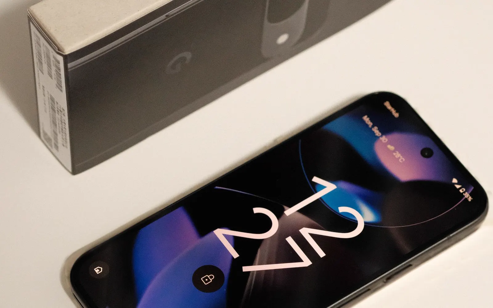 A Google Pixel 9 beside its box on a plain surface