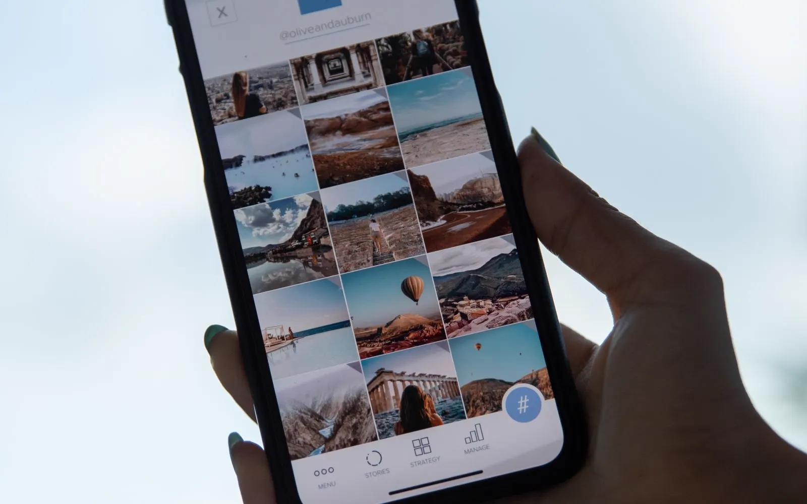 A hand holding a phone showing a grid of personal photographs