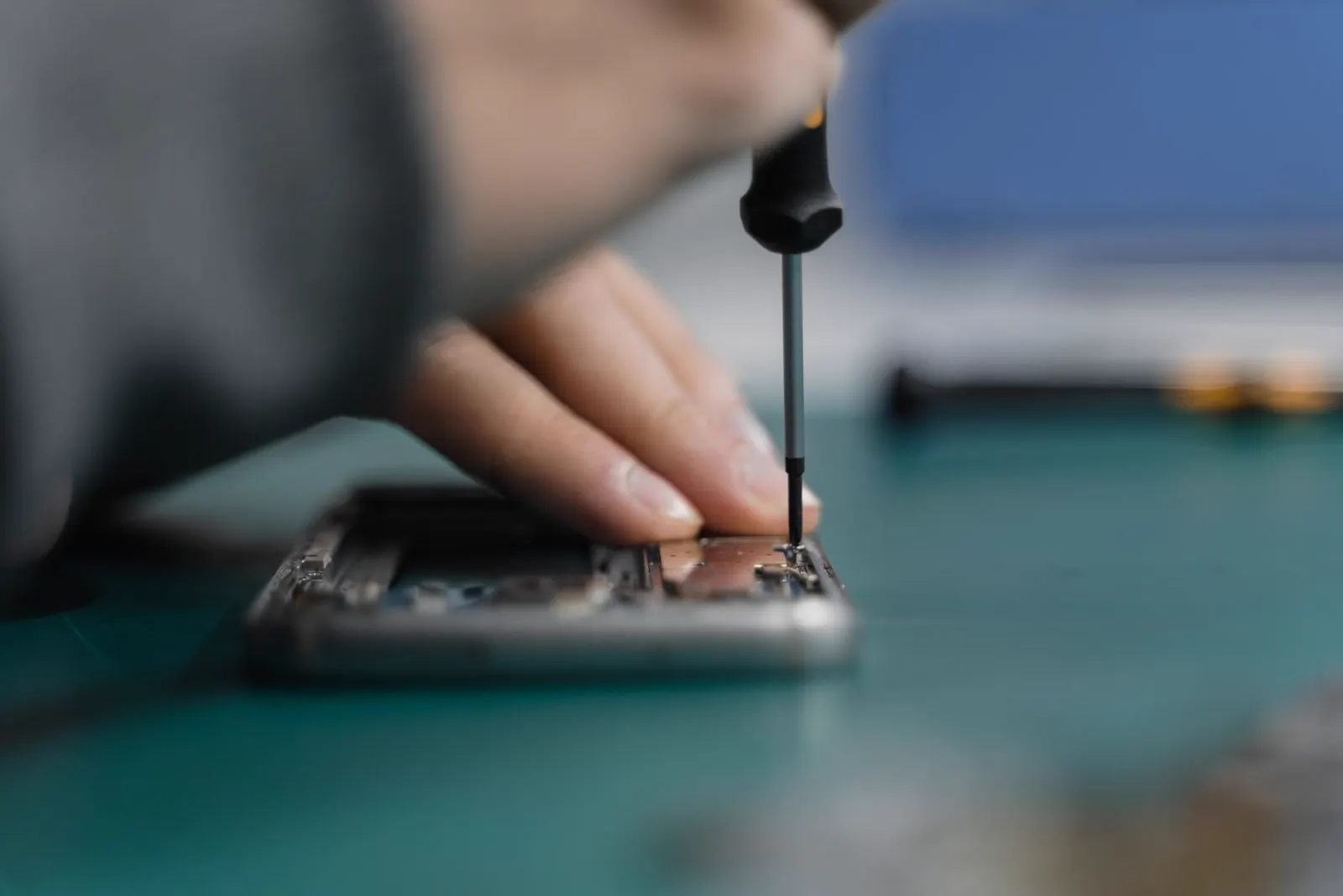 A technician using a precision screwdriver to repair the open internals of a smartphone