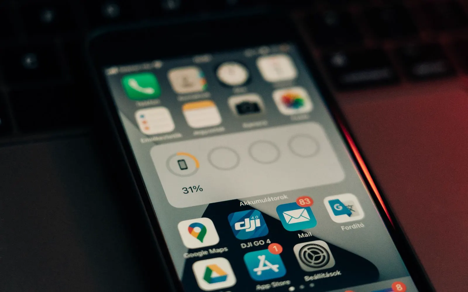 A phone resting on a keyboard showing its battery level