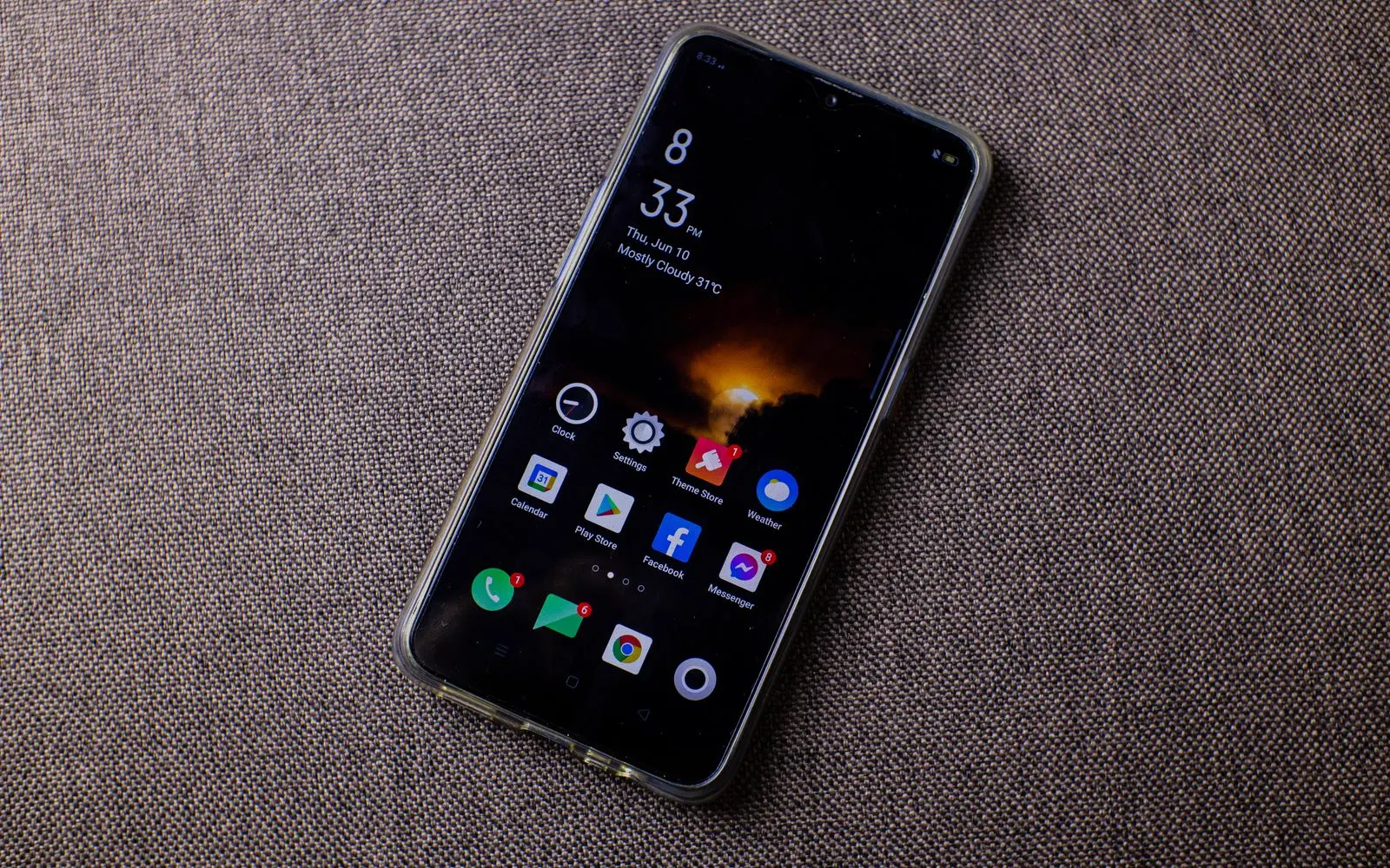 A phone on a textured surface showing a screen full of apps