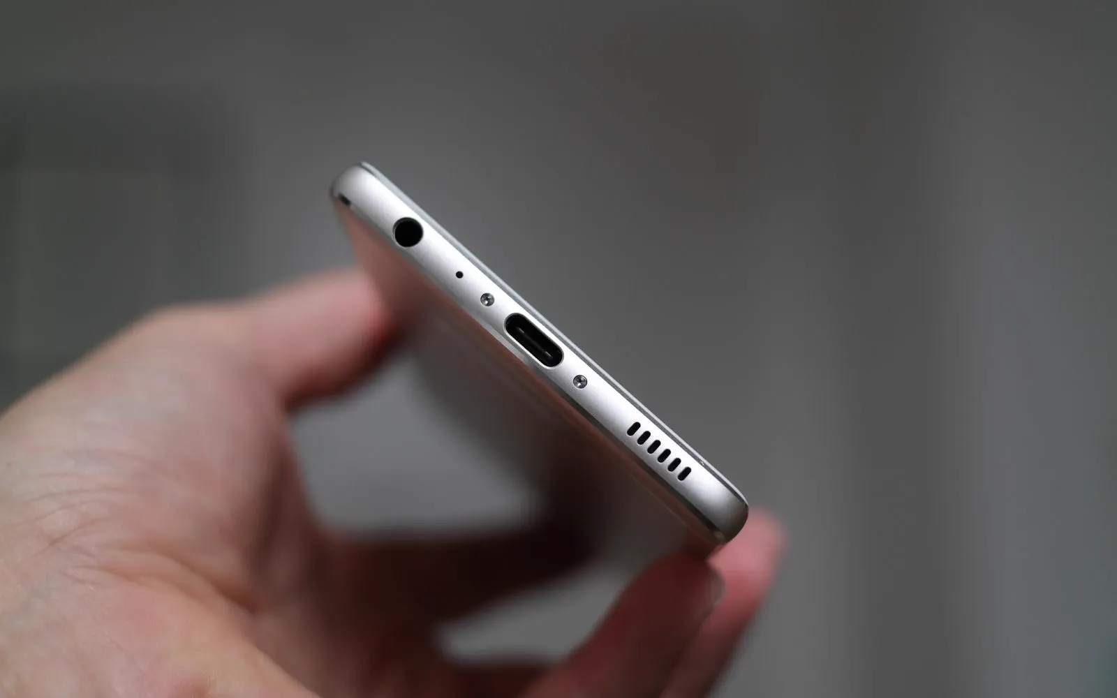 A hand holding a phone with its charging port in focus