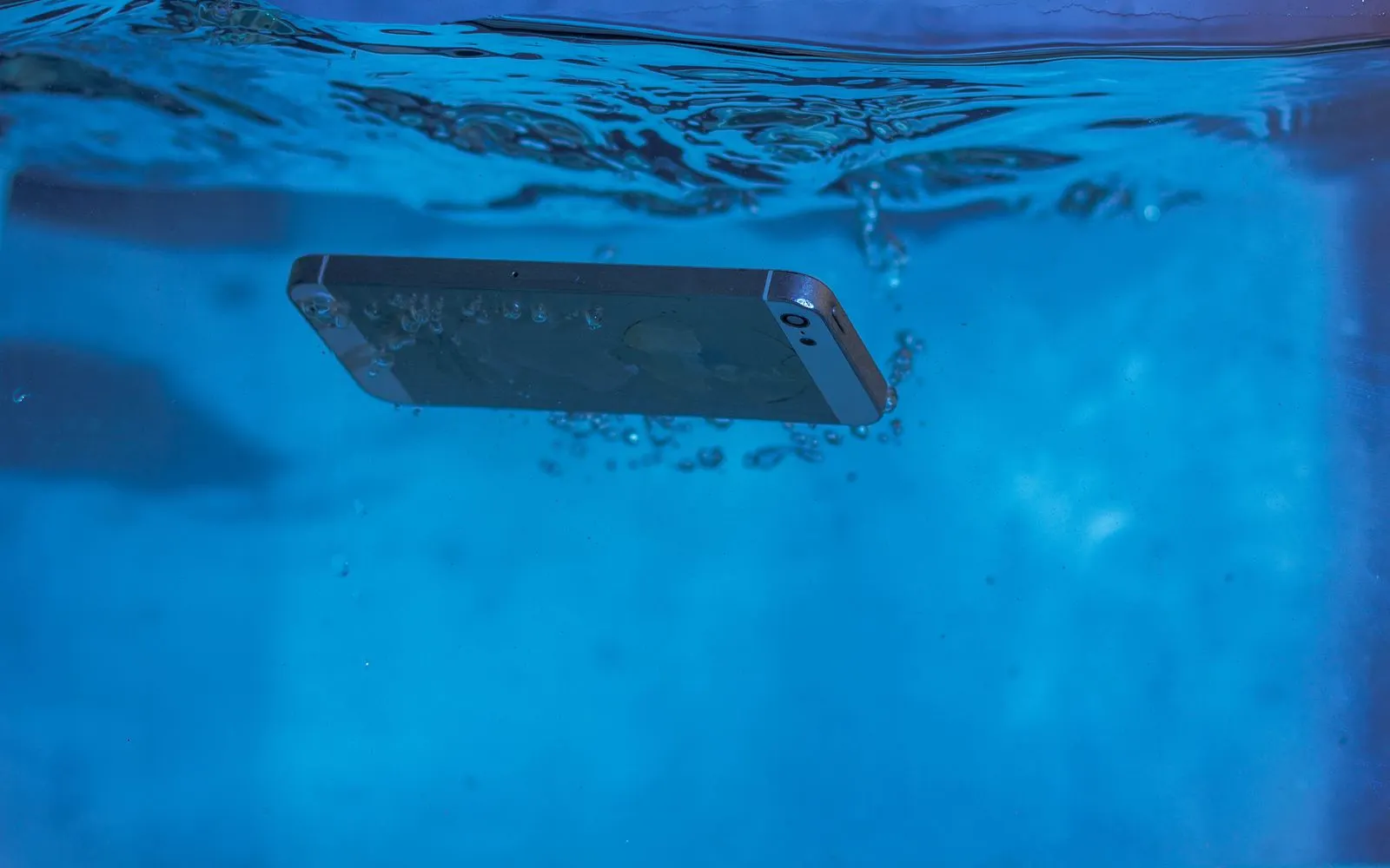 A smartphone underwater, air bubbles rising around it