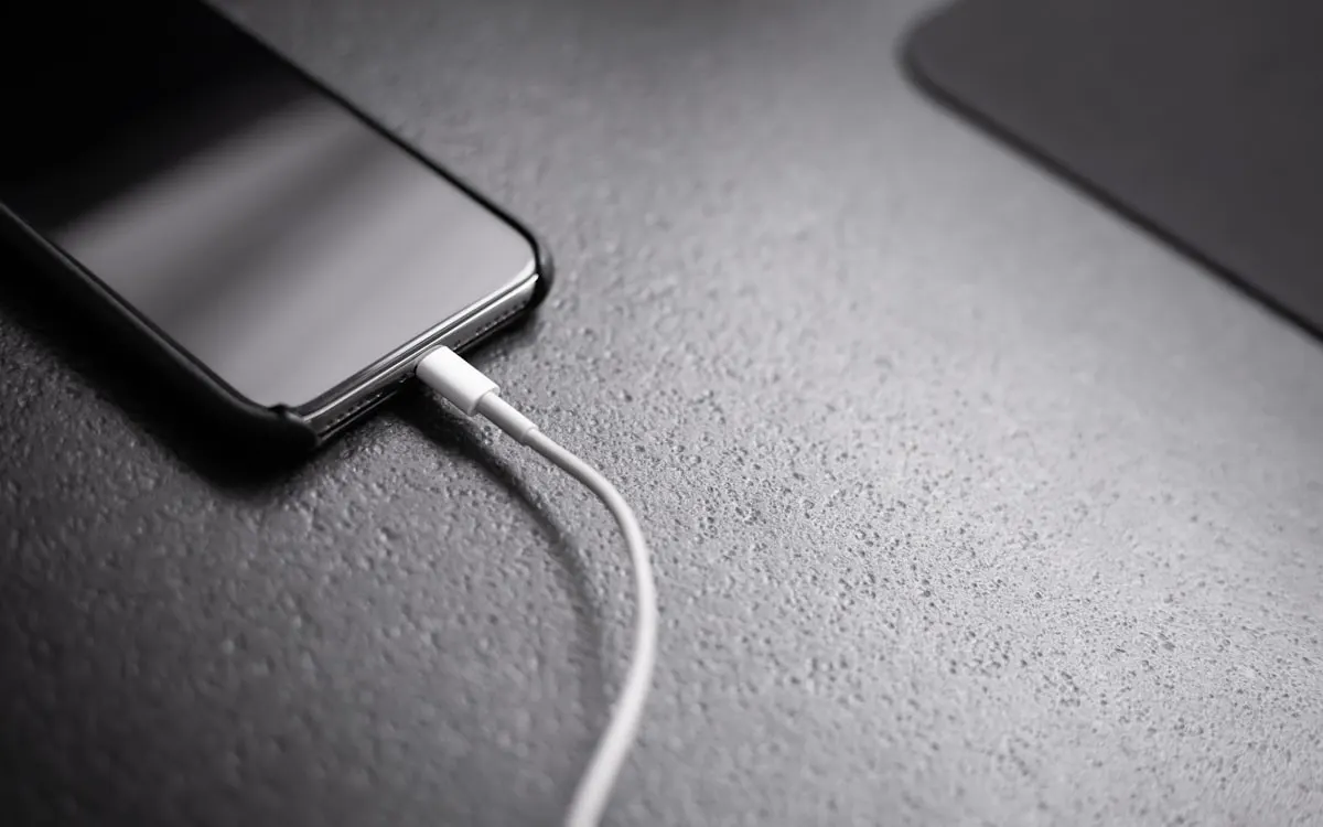 A smartphone resting on a desk on charge