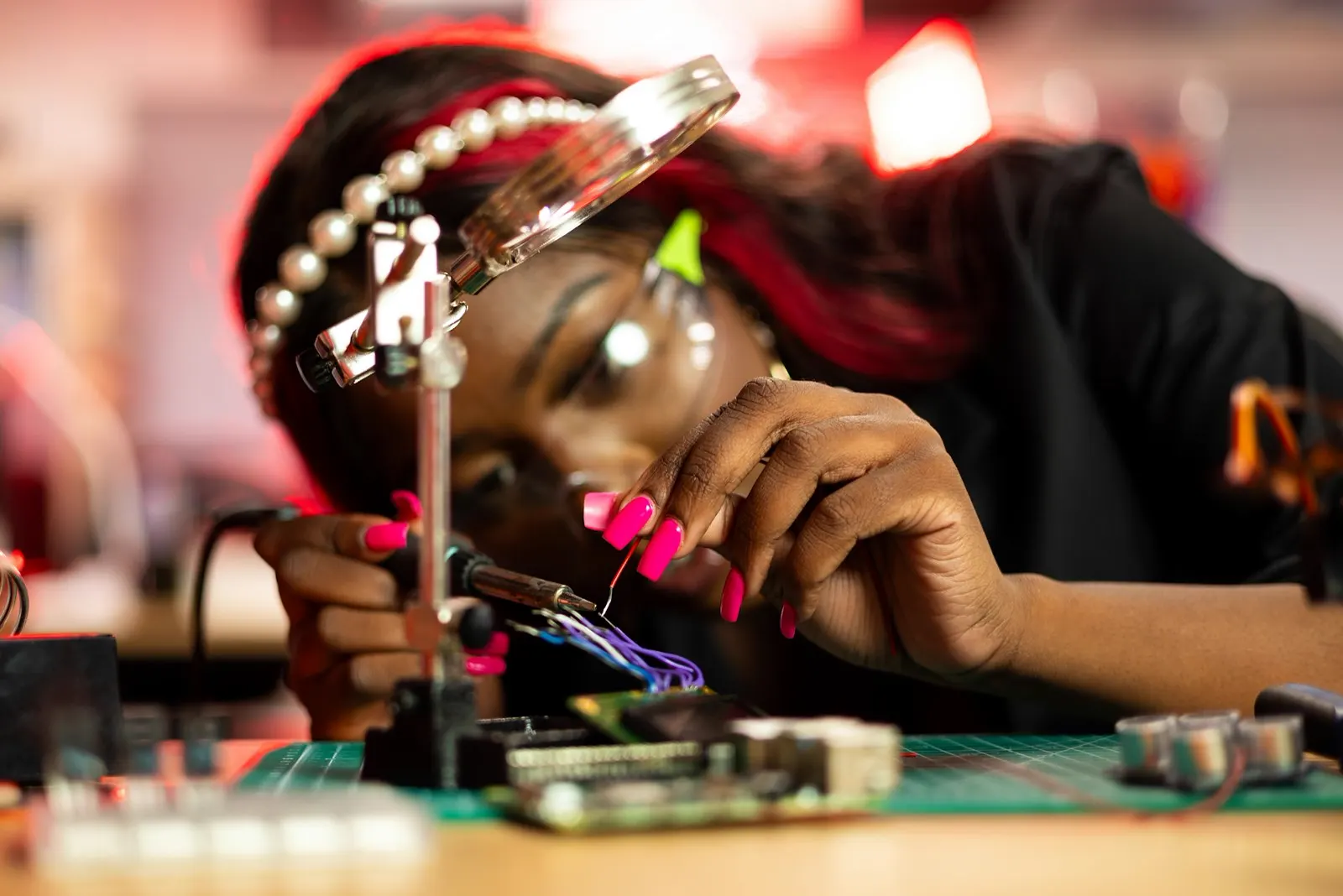 A technician working carefully on an open circuit board with a magnifying glass